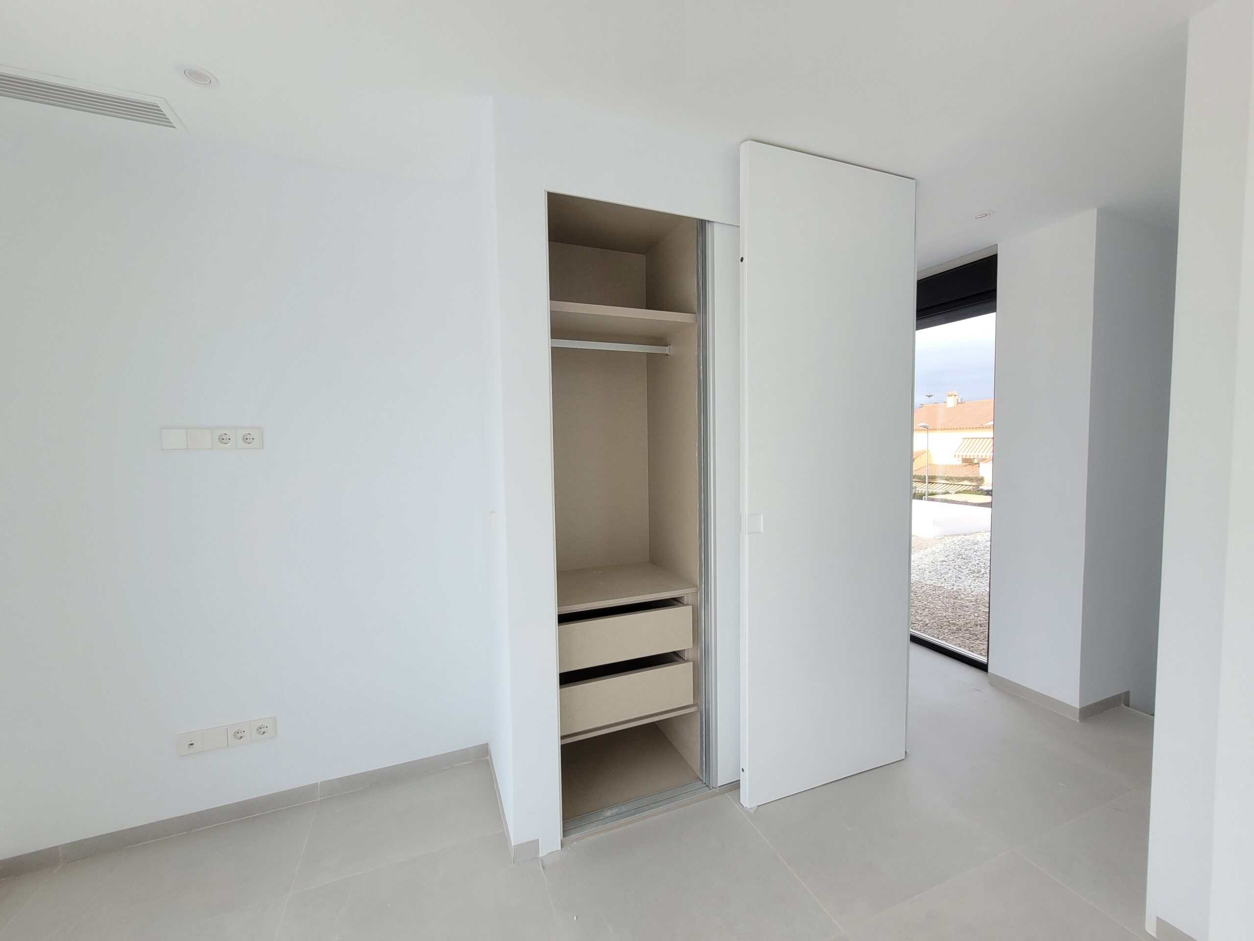 Eenvoudige witte ingebouwde kast met enkele laden in een moderne kamer.