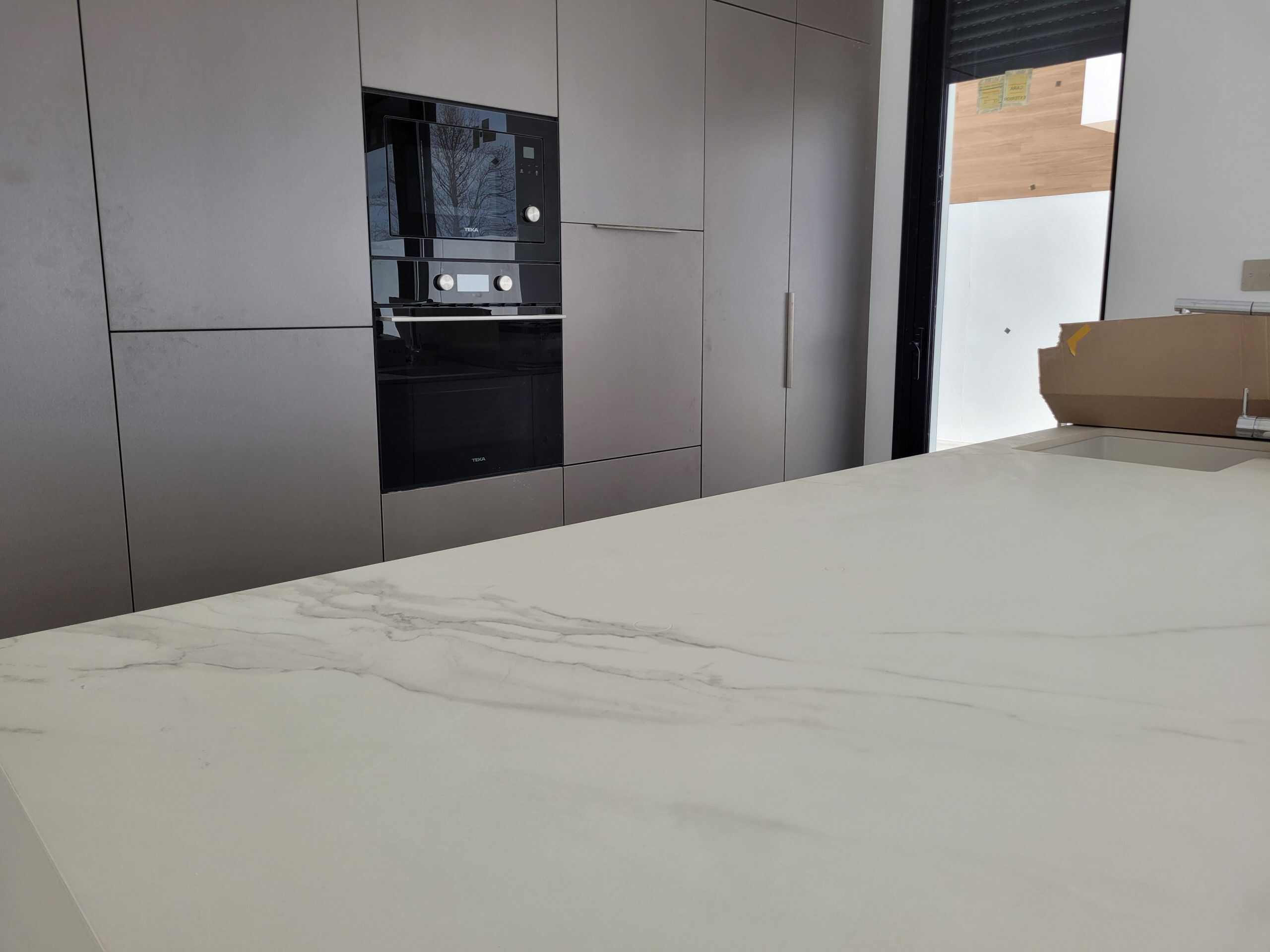 Luxury keuken met marmeren keukenblad en strak design, moderne inbouwapparatuur en grote raampartij.