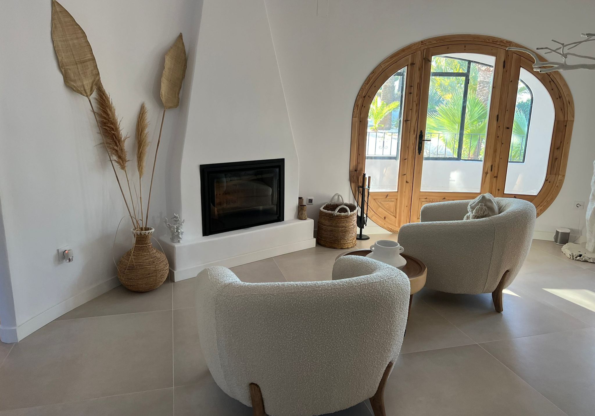 Rustieke woonkamer met modern design, grote ronde houten raam en knusse zitplaatsen.