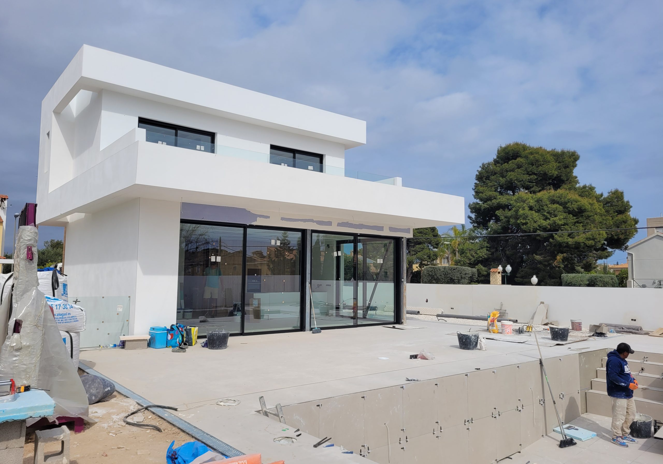 Modern wit gebouw onder constructie met glazen ramen en buitenruimte, perfect voor luxe woningen of resorts.