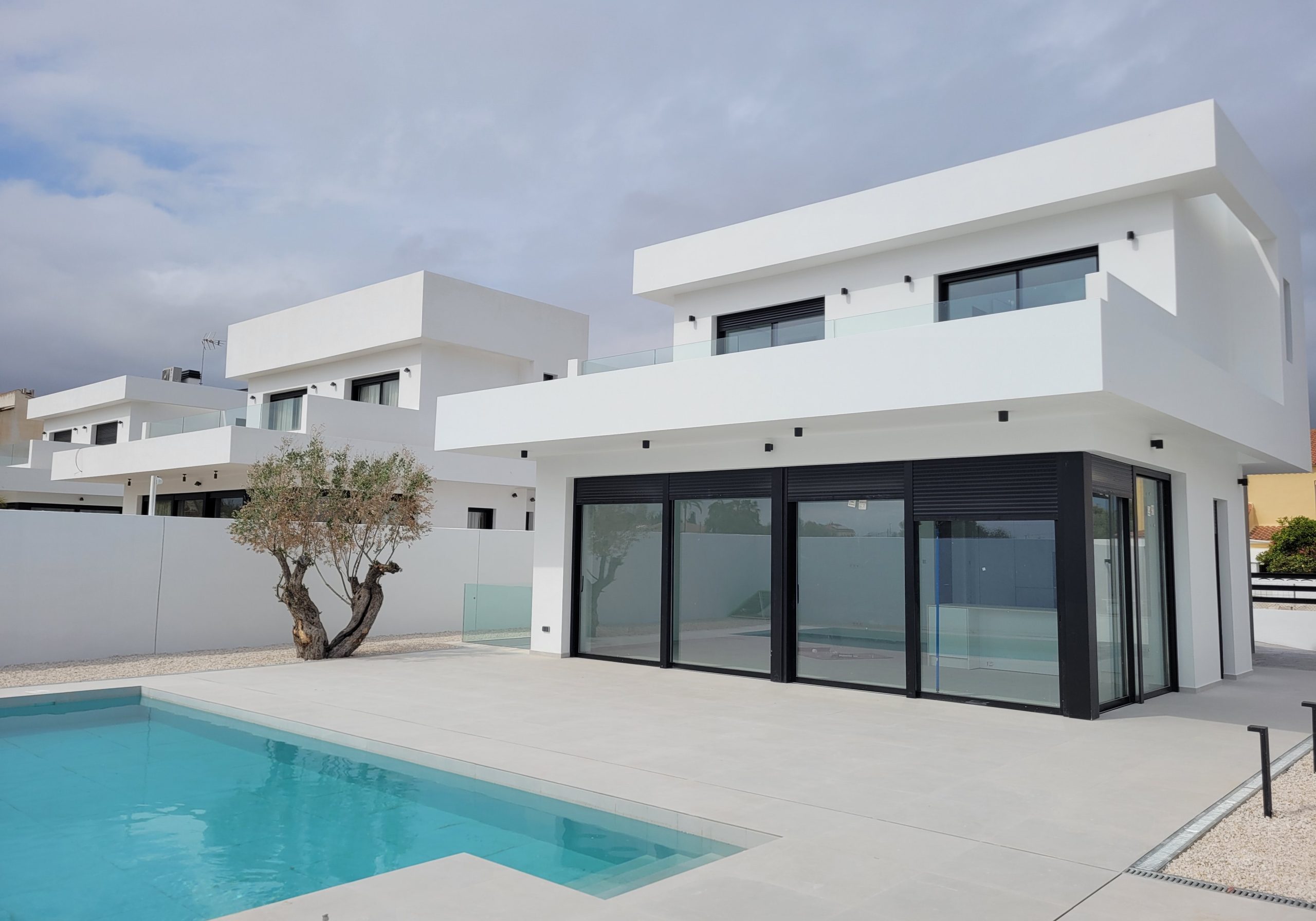 Moderne witte villa met grote glasramen en zwembad, ideaal voor luxe vakantiehuis of woonproject.